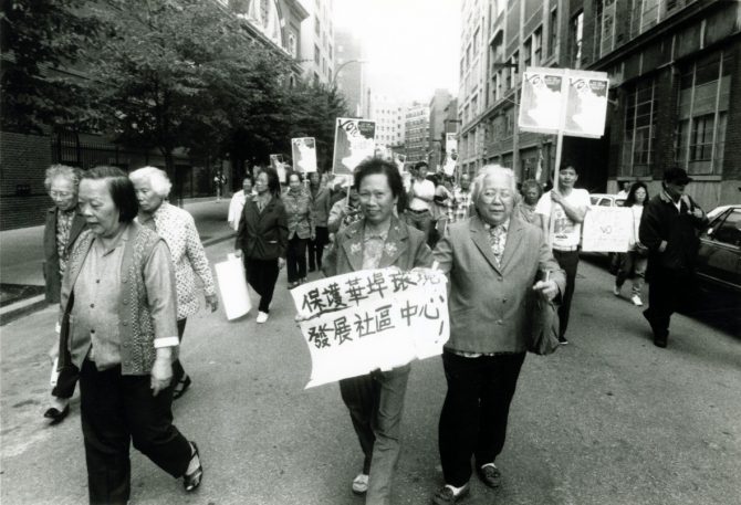 Protesters march in the street; many of them are carrying signs in Chinese text.